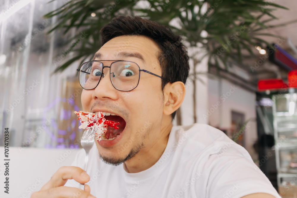 Φωτογραφία Funny happy face of asian man eating and putting cake into his mouth in the cafe