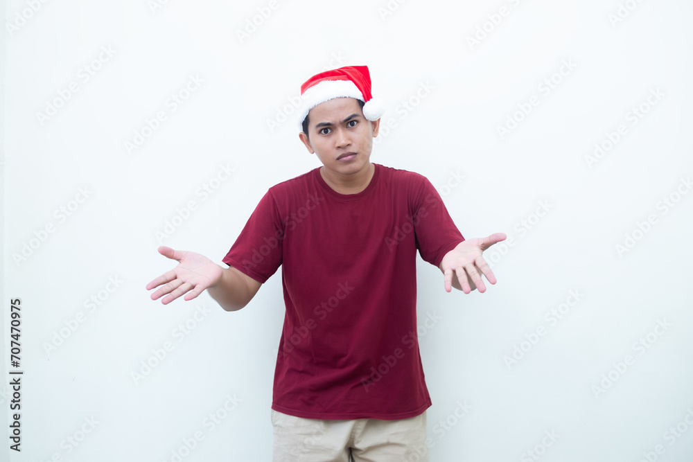 Young Asian man wearing a Santa Claus hat smiling, shock and pointing to her side isolated by white background for visual communication