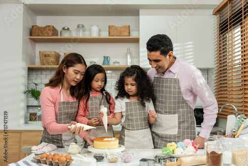 Asian attractive couple making cake with daughters in kitchen at house.