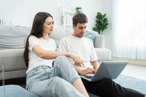 Caucasian young couple using laptop computer in living room at home.