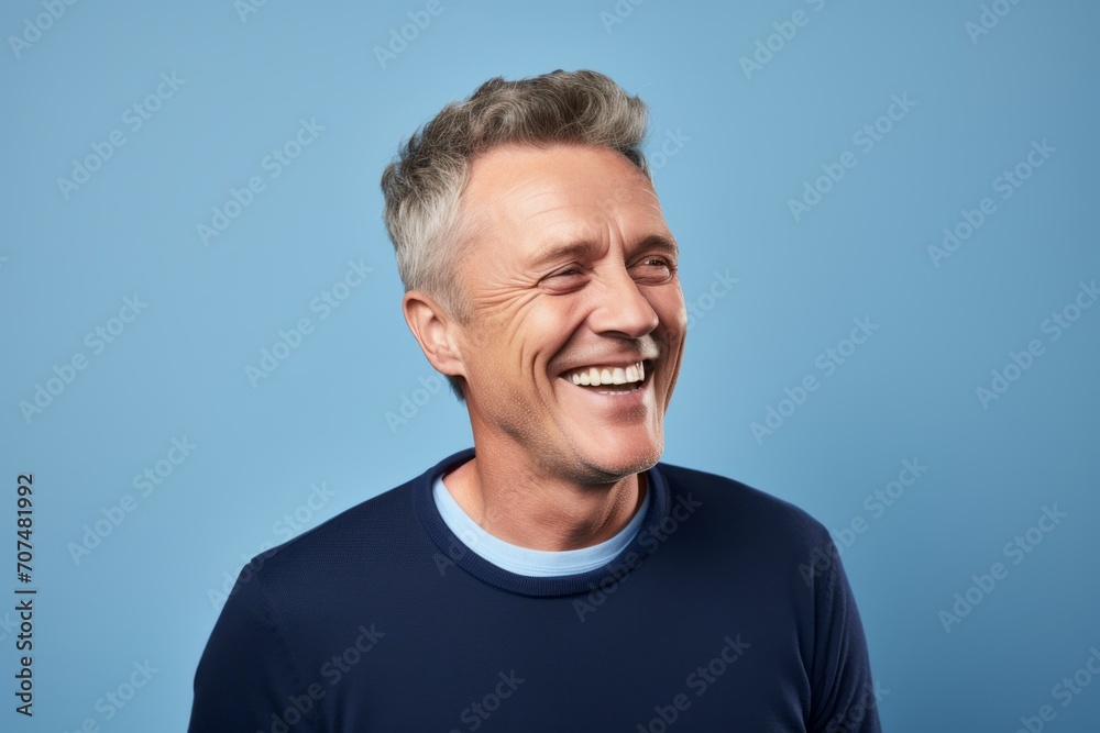 Portrait of happy mature man laughing and looking at camera against blue background Portrait of happy mature man laughing and looking at camera against blue background