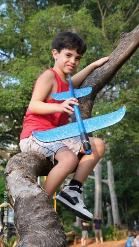 10 year old Brazilian holding his plane, hitting the tree trunk and warning that it is hollow.