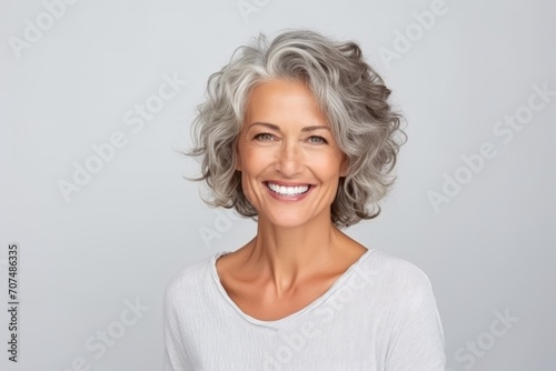 Portrait of a happy senior woman with grey hair over grey background