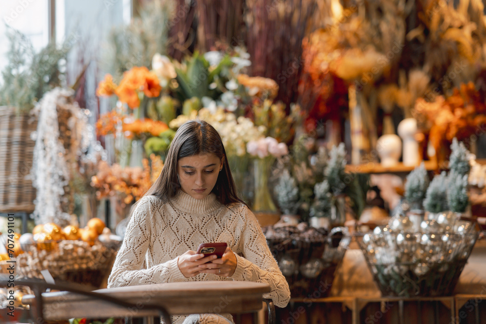 Exploring the decor shop, a young woman holds a phone in her hands.