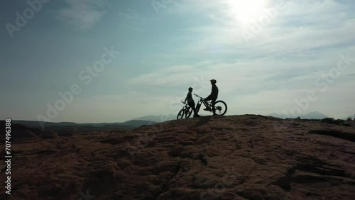 Mountain bike, extreme sports and silhouette or people relax during outdoor ride, desert journey or off road cycling. Sky, team conversation and dark shadow of cyclist on break after bicycle practice photo