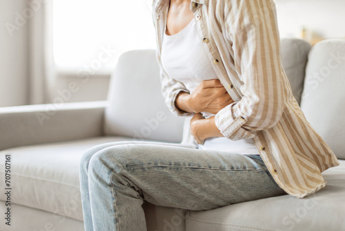 Uncomfortable young woman holding her abdomen, feeling unwell with stomach ache