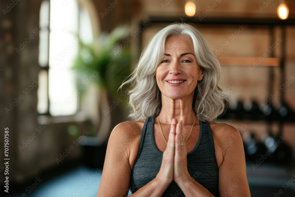 Smiling Mature woman meditating posing at a yoga studio Smiling Mature woman meditating posing at a yoga studio