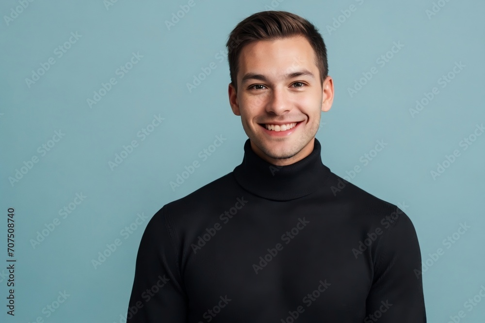 A handsome man wearing a black turtleneck sweater standing against the blue background. A handsome man wearing a black turtleneck sweater standing against the blue background.