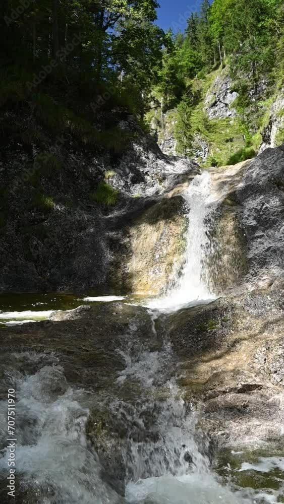A mountain stream with a fountain-like waterfall in summer, late afternoon, slow motion, vertial shot A mountain stream with a fountain-like waterfall in summer, late afternoon, slow motion, vertial shot
