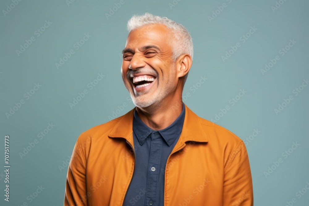 Portrait of a happy senior man laughing and looking at camera on blue background Portrait of a happy senior man laughing and looking at camera on blue background