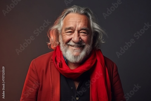 Portrait of a happy senior man with red scarf on dark background © Inigo