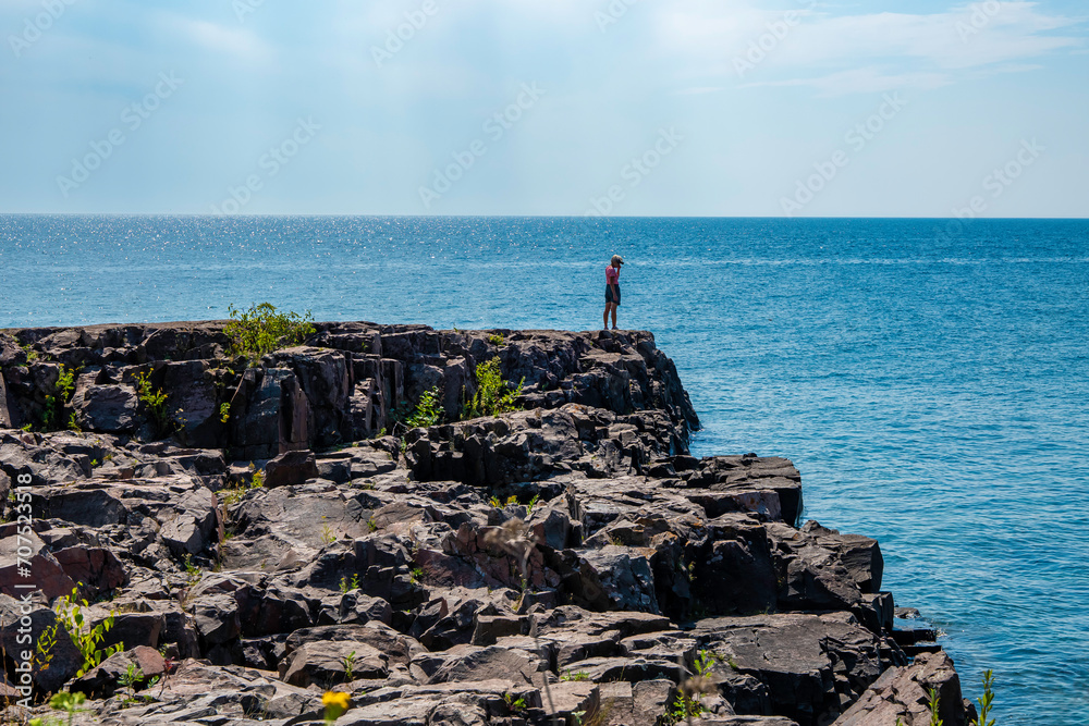 Unrecognizable person standing alone on the rocky North Shore of beautiful Lake Superior in Minnesota.