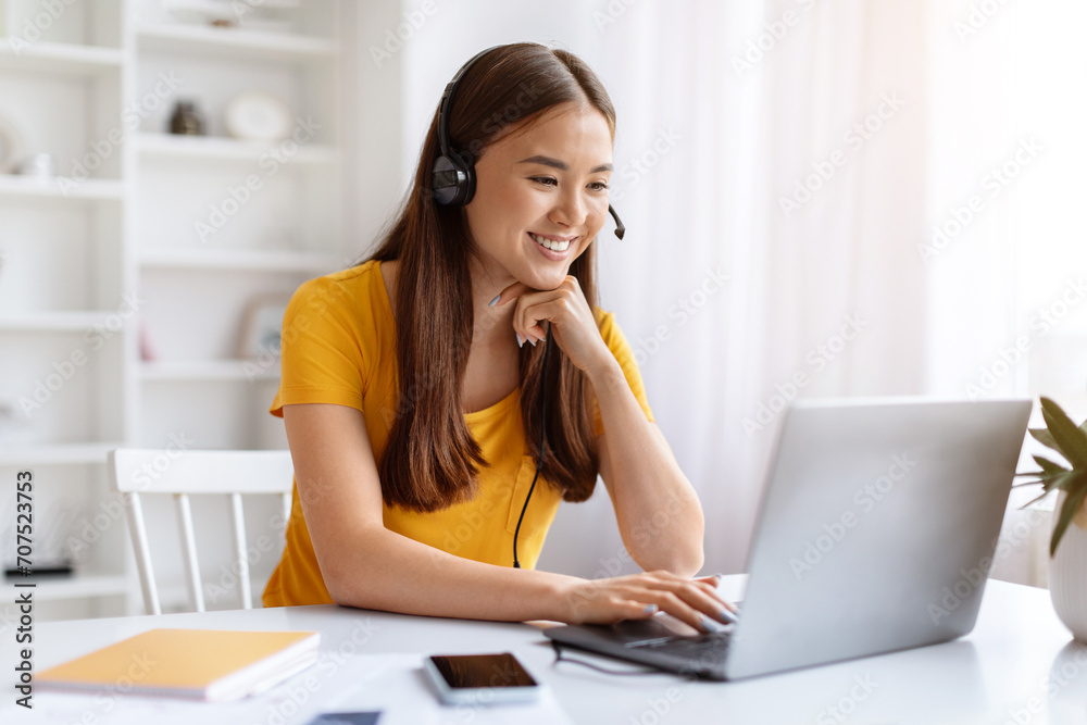 Beautiful Young Asian Woman Wearing Headset Watching Webinar On Laptop At Home Beautiful Young Asian Woman Wearing Headset Watching Webinar On Laptop At Home