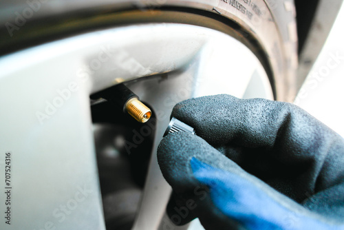 Car mechanic hand remove or close a tire valve cap of car wheel , Car maintenance service concept photo