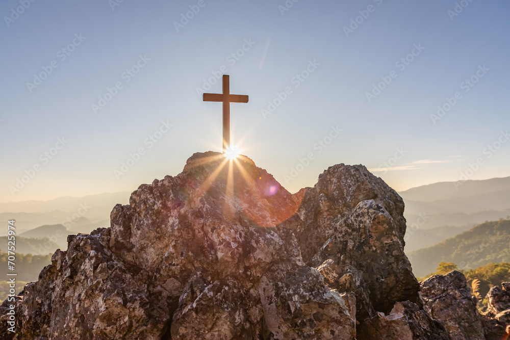 Silhouettes of crucifix symbol on top mountain with bright sunbeam on the colorful sky background