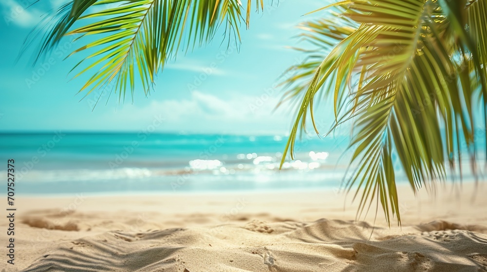 Fototapeta premium tropical sand beach scene with blue water wave and blurry green palm leaves in foreground, beach background concept with copy space for travel vacation