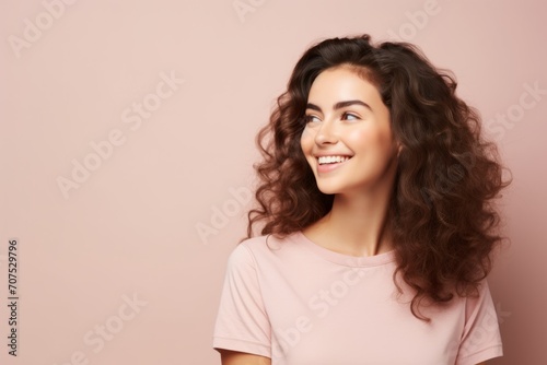 Portrait of beautiful young happy smiling woman with long curly hair  over pink background