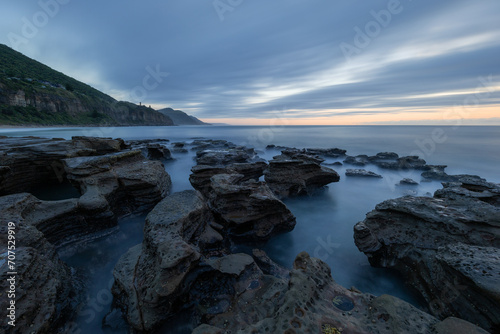 Long exposure view of rocky shore with cloudy sky.