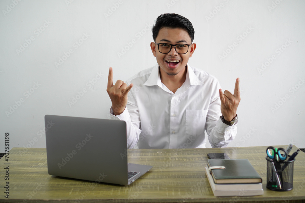 young asian businessman in a workplace making rock gesture wearing white shirt isolated young asian businessman in a workplace making rock gesture wearing white shirt isolated