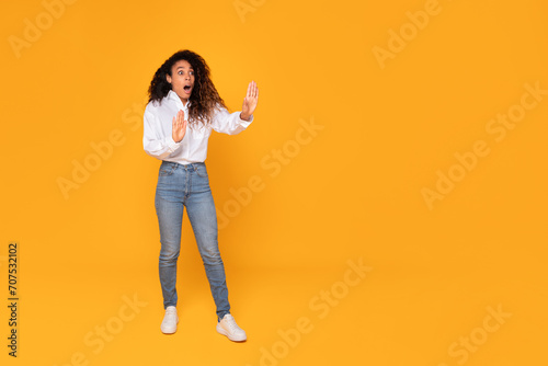 shocked black woman standing showing stop gesture over yellow background photo