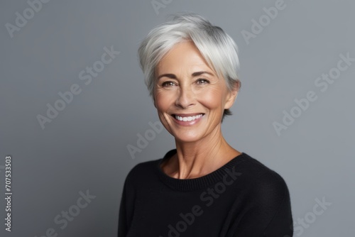 Portrait of a happy senior woman looking at camera over grey background