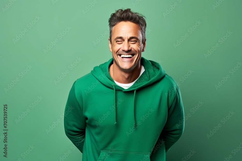 smiling man in green hoodie looking at camera on green background smiling man in green hoodie looking at camera on green background