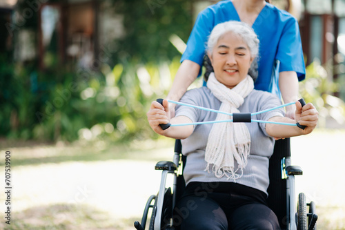 Asian physiotherapist helping elderly woman patient stretching arm during exercise correct with dumbbell in hand during training hand with patient Back problems in the garden.