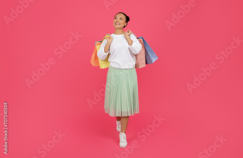 Dreamy Asian Shopaholic Lady Walking With Paper Shopper Bags In Hands