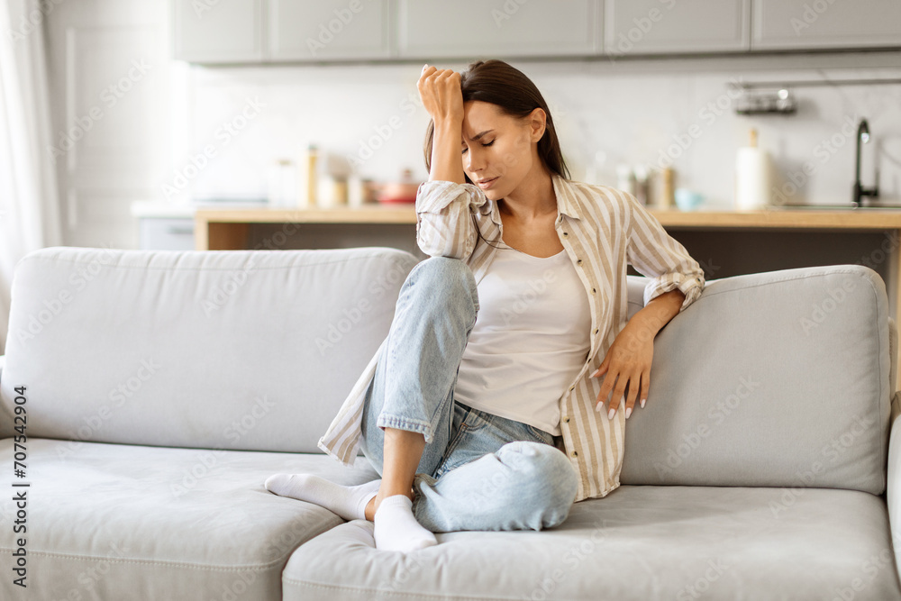 Depression Concept. Portrait Of Sad Young Woman Sitting On Couch At Home Depression Concept. Portrait Of Sad Young Woman Sitting On Couch At Home