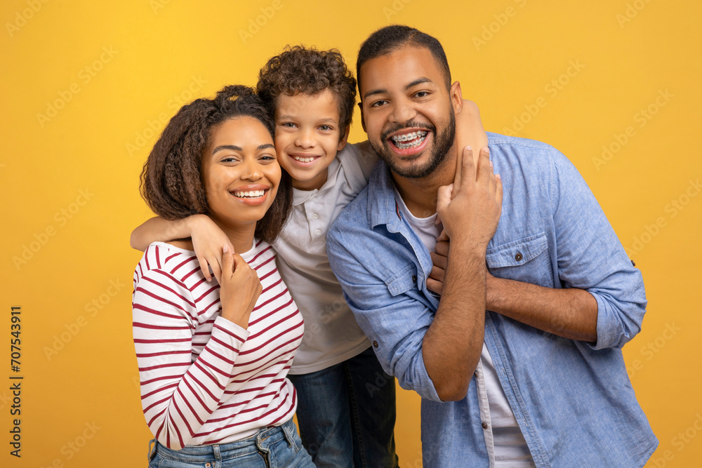 Obraz premium Happy African American family of three with preteen son embracing each other