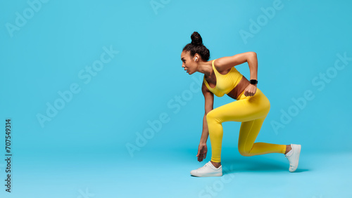 African American Woman Runner Doing Crouch Start Over Blue Background photo