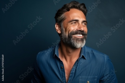 Portrait of a handsome mature man with beard and mustache over blue background.