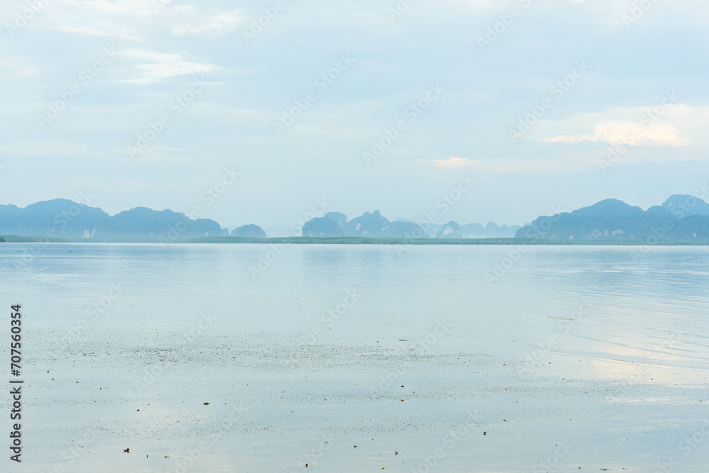 The distant mountains are complex, many with mangrove forests. There is a sea in front and a faint mist.