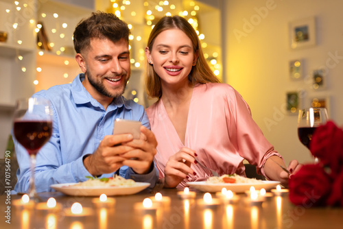 Couple enjoying shared moment on a phone at dinner
