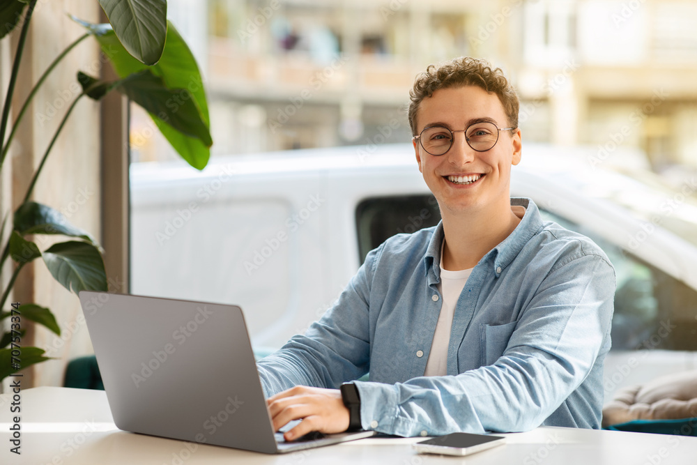 Smiling proud millennial european guy student in glasses, typing on computer Smiling proud millennial european guy student in glasses, typing on computer