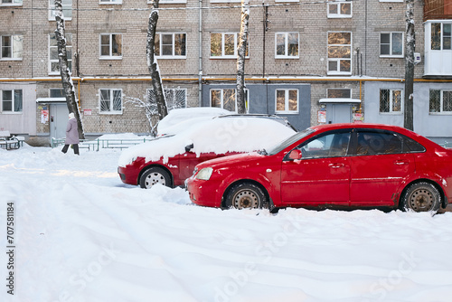 two red cars on ta brick house winter landscape. © Electrovenik