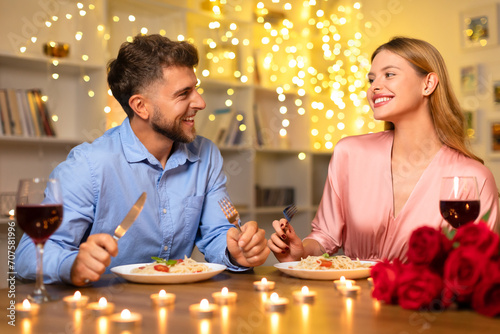 Happy couple enjoying romantic candlelit dinner with wine and pasta