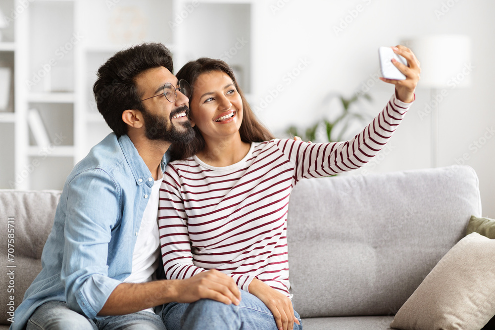 Indian man and woman taking selfie on smartphone at home - obrazy, fototapety, plakaty 