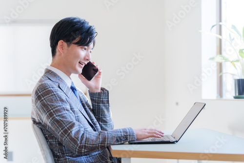 電話しながらノートパソコンで仕事するビジネスマン photo