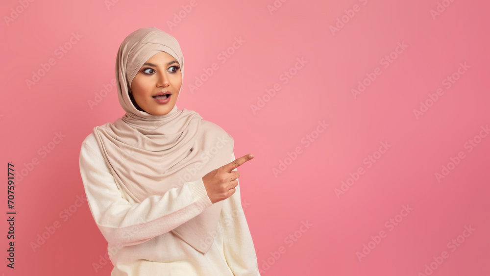 Astonished arab woman in hijab pointing aside at copy space Astonished arab woman in hijab pointing aside at copy space
