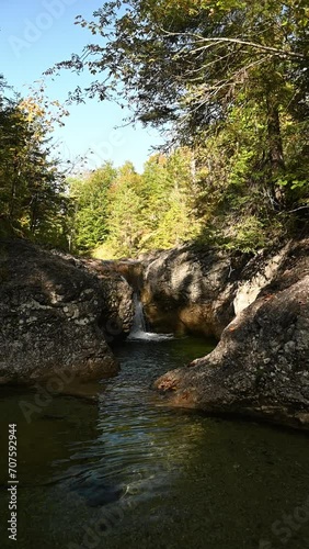 Vertical long shot of a waterfall and a mountain stream in autumn, slow motion