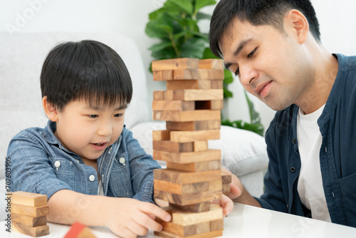 Asia Happy single father playing learning games janga with the little boy. Funny family is happy and excited in the house. Father and son having fun spending time together. holiday, weekend, vacant. photo