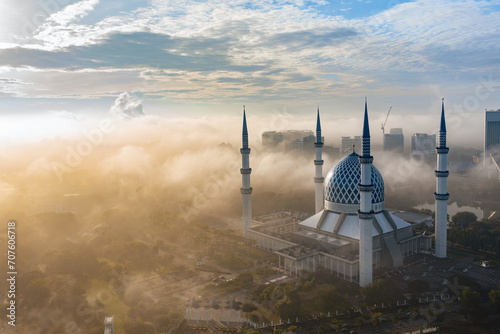 Close up aerial view of blue mosque of shah alam with low clouds and misty morning photo