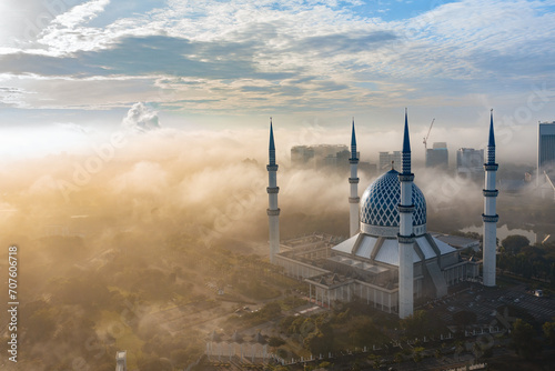 Close up aerial view of blue mosque of shah alam with low clouds and misty morning