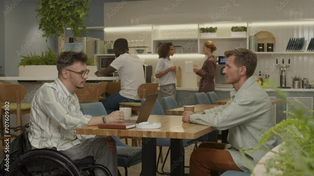 Man in wheelchair and his business partner having talk and shaking hands on meeting in modern coworking space Man in wheelchair and his business partner having talk and shaking hands on meeting in modern coworking space