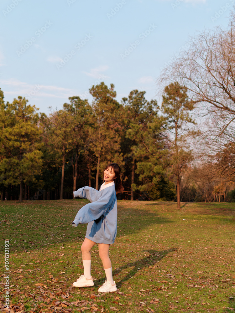 Beautiful young Chinese woman dancing with joy in sunny summer forest, wearing blue loose oversized top, mini skirt and white shoes. Emotions, people, beauty, youth and lifestyle portrait. Beautiful young Chinese woman dancing with joy in sunny summer forest, wearing blue loose oversized top, mini skirt and white shoes. Emotions, people, beauty, youth and lifestyle portrait.