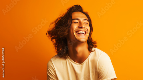 Handsome young male guy smile Asian with long red hair, on yellow orange background, banner, copy space, portrait.