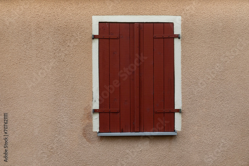 Wooden window with red closed shutters, Beige Wall with white Frame