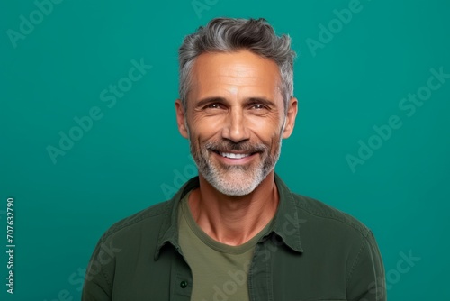 Portrait of handsome mature man with grey hair and beard. Isolated on green background
