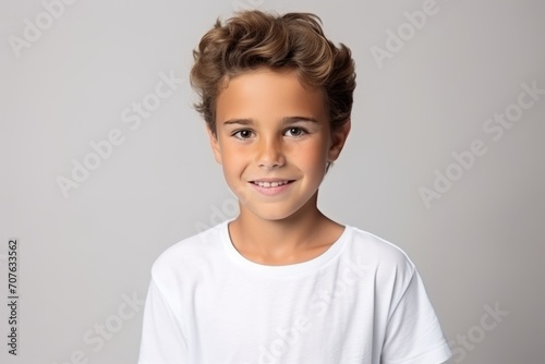 Portrait of a cute little boy in white t-shirt on grey background